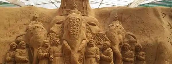 Sand sculpture of a elephant along with army surrounding it