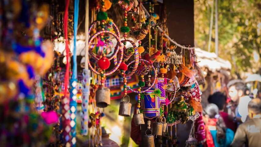 Colorful handcrafted items, including dreamcatchers and bells, displayed at a market stall. 