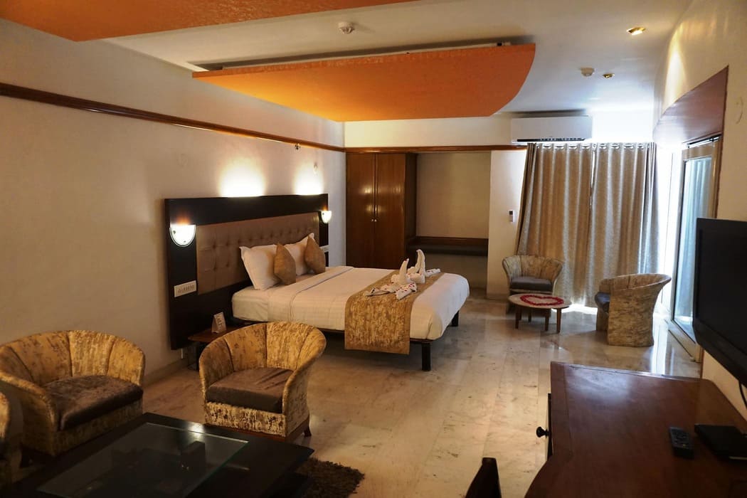 A well-appointed hotel room with a large bed, seating area, and subtle lighting.