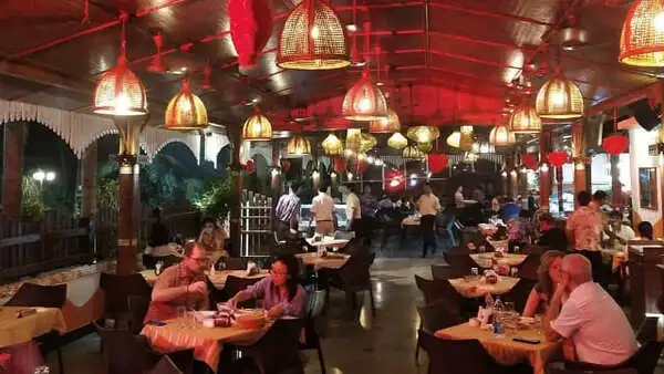 Lighted restaurant having people enjoying the food.