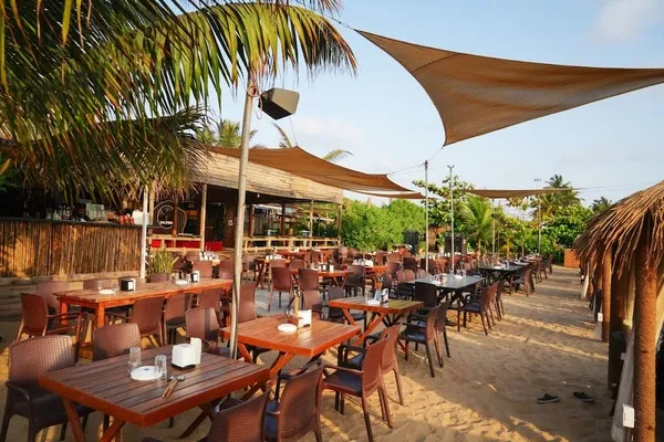A beachside restaurant, having tables placed over sand.